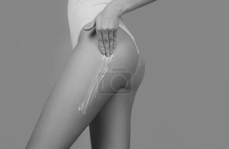 Téléchargez les photos : Perfect female buttocks. Cosmetic cream on woman buttocks with clean soft skin. Applying moisturizer cream on butt. Cellulite or anti cellulite treatment. Body care and spa salon concept - en image libre de droit
