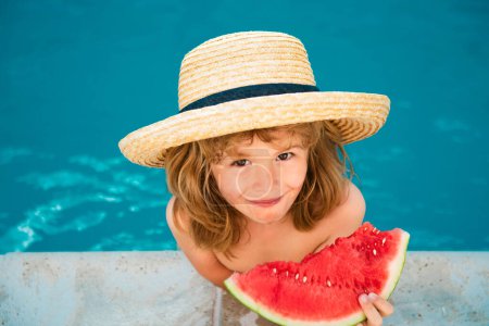 Foto de Niño feliz con rebanada de sandía dulce fresca sonriendo, mientras nada en la piscina en el día de verano - Imagen libre de derechos