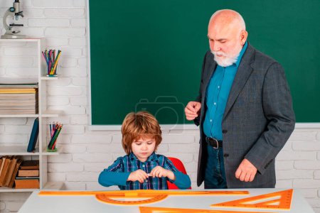 Photo for Pupil and Teacher in classroom. Elementary school teacher giving female pupil support in classroom - Royalty Free Image