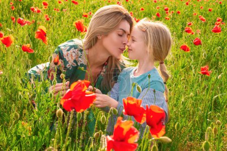 Foto de Mother with daughter on the poppies meadow. Beautiful mom and daughter on a poppy field outdoor. Poppies flowers - Imagen libre de derechos