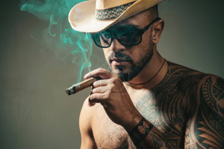 Téléchargez les photos : Des cigares cubains. Portrait de visage latin au look sensuel. Homme cubain fumant cigare et profiter de la vie et le moment. Concept humain. Temps de profiter - en image libre de droit