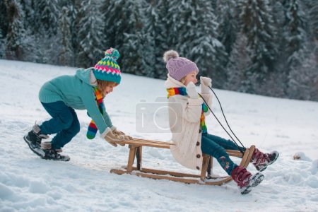Photo for Cute children boy and girl playing on a winter walk in nature. Winter knitted kids clothes. Cold weather. Happy little kids wearing knitted hat, scarf and sweater. Cold and snowy winter mountains - Royalty Free Image