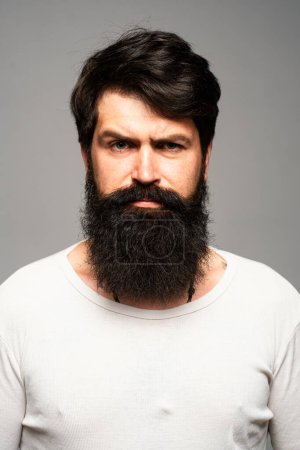 Foto de El retrato del hombre seguro serio tiene barba y bigote, se ve serio, aislado. Pensando tipo barbudo con estilo - Imagen libre de derechos