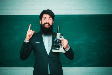 Photo for Serious male Student studying in school. Young bearded teacher near chalkboard in school classroom. Teachers day - knowledge and educational school concept. Education - Royalty Free Image