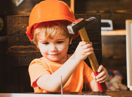 Téléchargez les photos : Petit garçon avec un marteau fait des réparations. - en image libre de droit