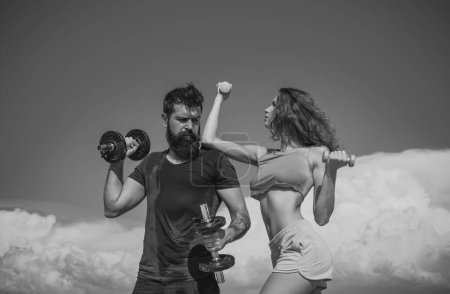 Photo for Sporty couple with dumbbell outdoors. Couple working out with dumbbells. Fitness club outside on sky - Royalty Free Image