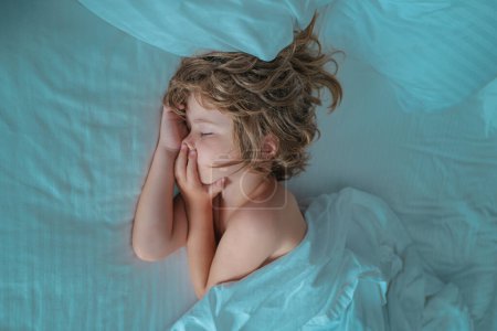 Téléchargez les photos : Les enfants dorment, vue de dessus. Enfant dans la chambre à coucher dormant sur lit avec drap blanc et oreiller - en image libre de droit