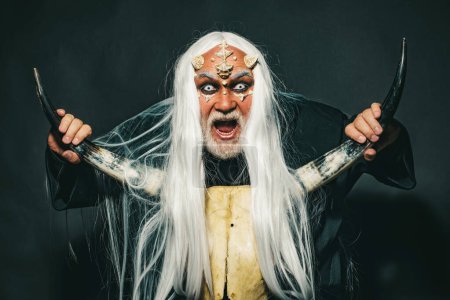Photo for Dracula - Halloween concept. Evil vampire man. Magic and fairy tale concept. Vampire man with white eyes. Burning diabolic demon summons evil forces and opens hell. Elderly man holding two red horns - Royalty Free Image