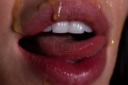 Photo for Sexy full lips. Honey dripping on sexy girl lips. Eating honey. Healthy food concept - Royalty Free Image