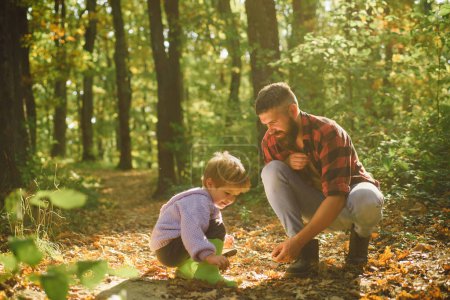 Foto de Padre e hijo en el parque de otoño divirtiéndose y riendo. Lindo niño con su padre durante un paseo por el bosque - Imagen libre de derechos