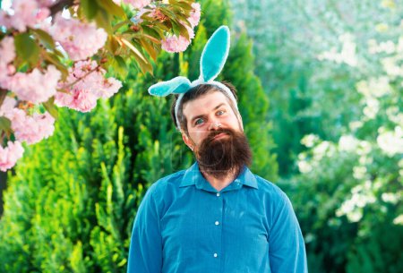Téléchargez les photos : Homme de Pâques drôle en costume de lapin avec des oreilles de lapin sur le jardin de printemps - en image libre de droit