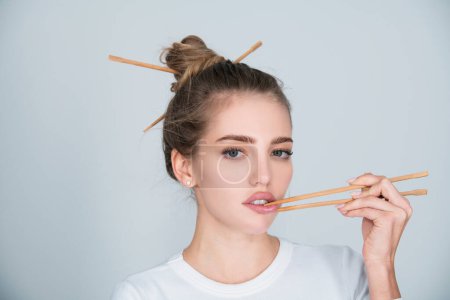 Foto de Sexy mujer sensual recogiendo labios con palillos. Boca sexy para publicidad de sushi. Estudio retrato aislado - Imagen libre de derechos