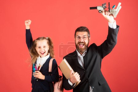 Téléchargez les photos : Professeur incroyable avec élève heureux excité écolière. Premier jour à l'école. Père et petite enfant écolière en première année - en image libre de droit