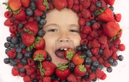 Téléchargez les photos : Fruits d'été. Mélange de baies. Les enfants font face avec des fruits de baies fraîches. Mélange assorti de baies fraise, myrtille, framboise, mûre sur fond. Baies nutritionnelles saines pour les enfants - en image libre de droit