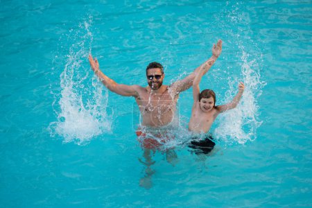 Téléchargez les photos : Père et fils dans la piscine en vacances d'été. Enfant avec papa jouant dans la piscine. Papa et enfant dans la piscine le jour de l'été. Loisirs et baignade pendant les vacances. Père s'amuser avec le fils dans la piscine - en image libre de droit