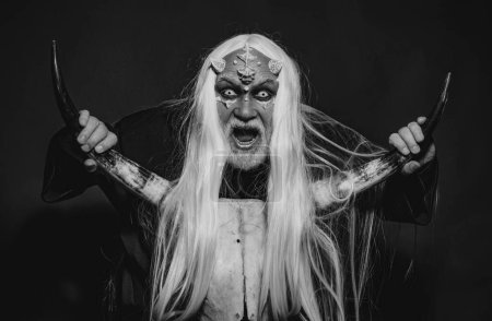 Photo for Dracula - Halloween concept. Evil vampire man. Magic and fairy tale concept. Vampire man with white eyes. Burning diabolic demon summons evil forces and opens hell. Elderly man holding two red horns - Royalty Free Image