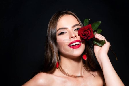 Foto de Retrato de cerca de una joven hermosa mujer sexy con rosa roja sobre un fondo negro. Primer plano fresco cara chica - Imagen libre de derechos