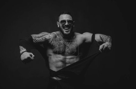 Photo for Angry guy. Fashion brutal guy with sexy body ripped shirt. Sexy man with muscular body and bare torso - Royalty Free Image