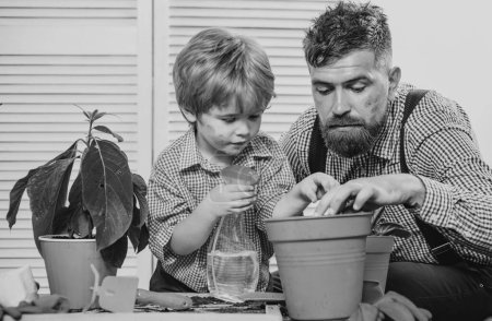 Photo for Child son with father growing plant in pot. Family holiday and togetherness. Little cute boy helps his parents. Happy family planting sprout in a plant pot - Royalty Free Image