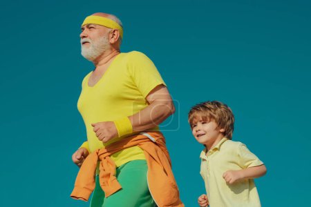 Foto de Abuelo y nieto corriendo en la naturaleza soleada. Concepto de estilo de vida saludable. Como los deportes. Abuelo y nieto corriendo afuera en el parque - Imagen libre de derechos