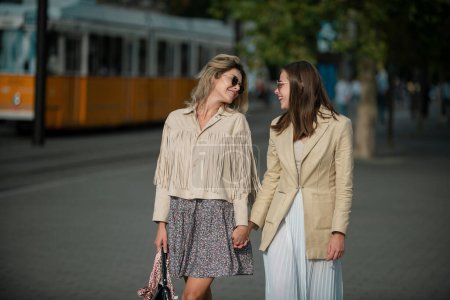 Téléchargez les photos : Portrait extérieur de jeunes femmes caucasiennes heureuses profitant d'une bonne journée. Jolies jeunes filles qui s'amusent à l'extérieur ensemble. Mode de vie humeur urbaine. Meilleurs amis portant tenue décontractée - en image libre de droit