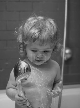 Téléchargez les photos : Bébé drôle enfant baigné de mousse et se lavant dans la baignoire à la maison - en image libre de droit