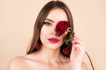 Foto de Sexy woman lips with red lipstick and beautiful red rose. Beautiful young pretty woman with healthy skin and red rose near face - Imagen libre de derechos