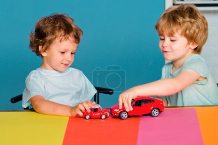 Foto de Divertido niño divirtiéndose y jugando con el coche de juguete. Feliz lindo chico inteligente alumno en el preescolar. Niño lindo en el aula - Imagen libre de derechos