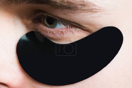 Photo for Skin care. Black pearl extract. Minimizes puffiness and reduce dark circles. Eye patches for men. Man with black eye patches close up. Metrosexual concept. Focused treatments for under eye area. - Royalty Free Image