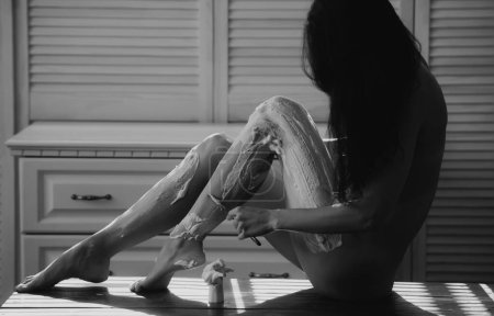 Foto de Concepto de cuidado corporal. Sexy chica afeitándose las piernas. Epilación, depilación o mujer sin pelo. Depilación de la línea. Mujer desnuda con las piernas de afeitar hoja de afeitar. Peluquería - Imagen libre de derechos