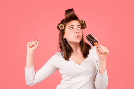 Téléchargez les photos : Femme drôle chantant avec peigne. Femme brossant les cheveux sains avec un peigne. Se soucie d'un cheveu sain et propre. Concept de salon de beauté - en image libre de droit