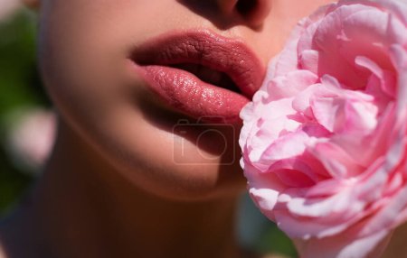 Téléchargez les photos : Rose rose tendre. Les lèvres, ça compte. Maquillage naturel des lèvres. Tendresse womans lèvres avec rose rose. Femme de tendresse. Concept de soins et de tendresse lèvres pleines dodues - en image libre de droit