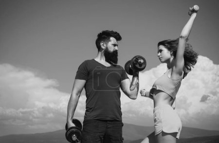Photo for Sporty couple with dumbbell outdoors. Couple working out with dumbbells. Strong man and sexy woman working out with dumbbells - Royalty Free Image
