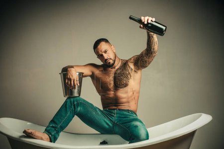 Photo for Man on sexy party with bottle of champagne on grey background - Royalty Free Image