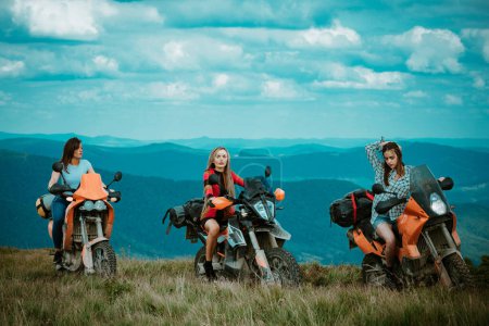 Téléchargez les photos : Groupe de femme sexy sur moto. Femme cavalière, filles actives chevauchant sur la moto en vélo tour sur route forestière, concept de montagne aventure. Racer fille amis sur motocross - en image libre de droit