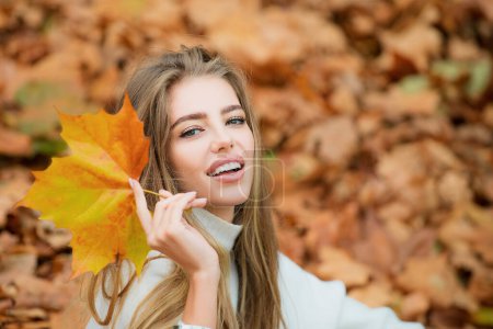 Téléchargez les photos : Heureuse femme souriante tenant dans ses mains des feuilles d'érable jaune sur fond d'automne - en image libre de droit