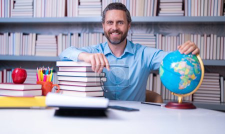 Photo for Portrait of school teacher with book in classroom. Handsome teacher in classroom. Teachers Day. Good school teacher. Tutor at classroom. Man with books in classroom. Knowledge and education concept - Royalty Free Image
