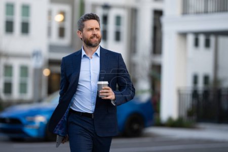 Photo for Businessman walking in city. Gray hair business man walk on city street. Business man walking outdoor, hold take away coffee cup. Business man in suit go to office work. Successful business - Royalty Free Image