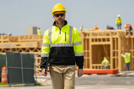 Photo for Construction worker with hardhat helmet on american construction site. Construction engineer worker in builder uniform on construction. Portrait of builder ready to build new house - Royalty Free Image