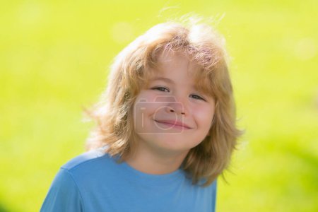 Photo for Funny kids emotions. Outdoor close up portrait of a cute little child playing outdoor. Cute funny blonde little child close up portrait on green grass background - Royalty Free Image