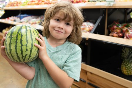Photo for Child with watermelon shopping at supermarket. Grocery store, shopping basket. Banner with kids for grocery food store or supermarket. Child choosing food in store or grocery store - Royalty Free Image