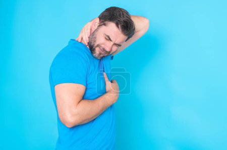 Photo for Man feeling migraine head strain. Tired bored man has headache. Exhausted man struggle with migraine or headache. Guy having a headache, isolated on studio blue background - Royalty Free Image