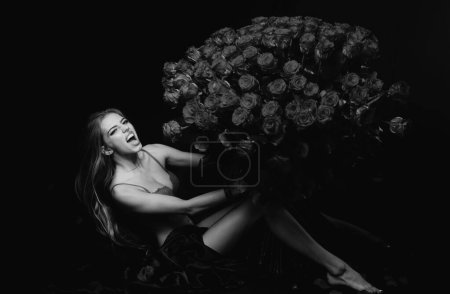 Téléchargez les photos : Sexy femme sensuelle avec bouquet de roses. Fille en lingerie rouge avec Valentines présent. Cadeau avec amour - en image libre de droit