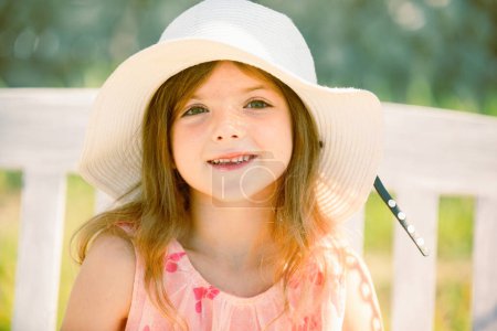 Foto de Summer kids girl outdoor, child cute face. Cute little girl swinging on the meadow in summer day - Imagen libre de derechos