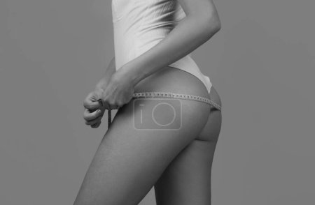 Foto de Young girl with perfect buttocks with a measuring tape. Sexy booty, ass - Imagen libre de derechos