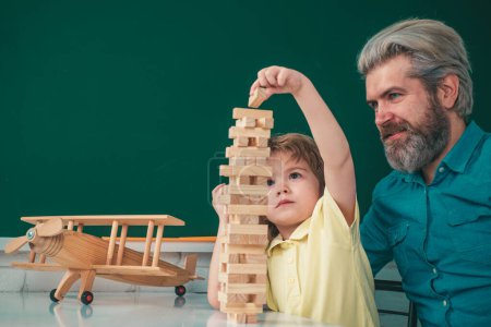 Photo for Father and son playing Jenga games. Hand movement control Building Computational Skills. Childrens play concept - Royalty Free Image