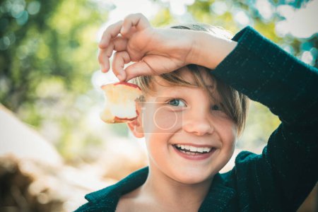 Foto de Niño en el sombrero sosteniendo manzana y se acuesta en el heno. Lindo niño pequeño sosteniendo la hoja de oro en el fondo de la aldea granja. Vitaminas en otoño. Lindo niño - Imagen libre de derechos