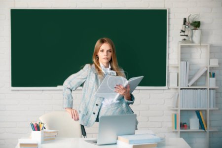 Photo for Portrait of young clever smart female college student studying in classroom on class with blackboard background - Royalty Free Image