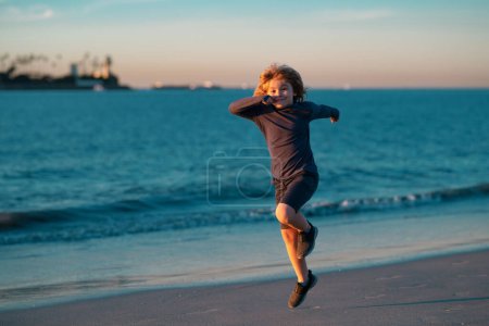 Téléchargez les photos : Les enfants courent dehors. Course et sport sain pour les enfants. Enfant courant sur un terrain d'été près de la mer, enfants en forme. Vacances d'été avec enfant - en image libre de droit