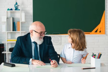 Photo for School lessons. Education and learning. Old teacher with pupil in classroom - Royalty Free Image